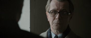 Movie still from “Tinker Tailor Soldier Spy” (2011), directed by Tomas Alfredson – An older man wearing a suit and tie; Close Up shot, Over the shoulder angle