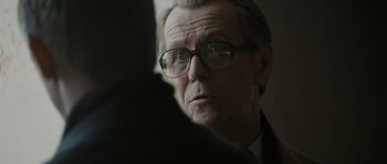 Movie still from “Tinker Tailor Soldier Spy” (2011), directed by Tomas Alfredson – An older man wearing glasses looking at the camera; Close Up shot, Over the shoulder angle