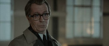 Movie still from “Tinker Tailor Soldier Spy” (2011), directed by Tomas Alfredson – A person wearing a suit and glasses; Close Up shot, Over the shoulder angle