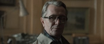 Movie still from “Tinker Tailor Soldier Spy” (2011), directed by Tomas Alfredson – An older man wearing glasses and wearing a jacket; Close Up shot, Over the shoulder angle