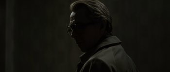 Movie still from “Tinker Tailor Soldier Spy” (2011), directed by Tomas Alfredson – A man with glasses is looking at the camera; Close Up shot, Over the shoulder angle