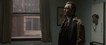 Movie still from “Tinker Tailor Soldier Spy” (2011), directed by Tomas Alfredson – A man standing in front of a window in a room; Medium shot, Over the shoulder angle