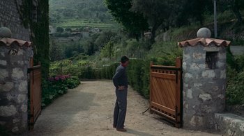 Movie still from “To Catch a Thief” (1955), directed by Alfred Hitchcock – A man standing in front of a wooden gate; Extreme Wide shot, High angle