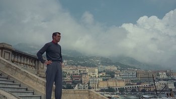 Movie still from “To Catch a Thief” (1955), directed by Alfred Hitchcock – A man standing on the side of a building looking out at a city; Wide shot, Low angle