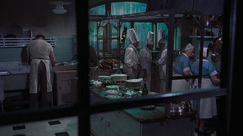 Movie still from “To Catch a Thief” (1955), directed by Alfred Hitchcock – A group of people in a kitchen preparing food; Wide shot, High angle