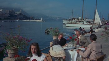 Movie still from “To Catch a Thief” (1955), directed by Alfred Hitchcock – A group of people sitting at a table near the water; Wide shot, High angle