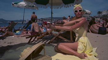 Movie still from “To Catch a Thief” (1955), directed by Alfred Hitchcock – A woman in a yellow bathing suit sitting on the beach; Medium shot, High angle