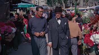 Movie still from “To Catch a Thief” (1955), directed by Alfred Hitchcock – Two older men walking down a crowded street; Medium shot, Low angle