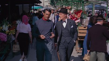 Movie still from “To Catch a Thief” (1955), directed by Alfred Hitchcock – Two men walking down the street talking to each other; Medium shot, Over the shoulder angle