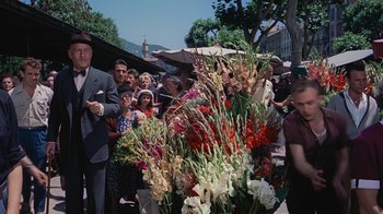 Movie still from “To Catch a Thief” (1955), directed by Alfred Hitchcock – A group of people standing around a bunch of flowers; Wide shot, High angle