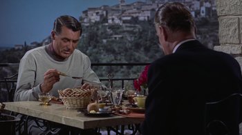 Movie still from “To Catch a Thief” (1955), directed by Alfred Hitchcock – Two men are sitting at a table with food; Medium shot, Over the shoulder angle