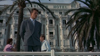 Movie still from “To Catch a Thief” (1955), directed by Alfred Hitchcock – A man in a suit standing in front of a building; Wide shot, Low angle