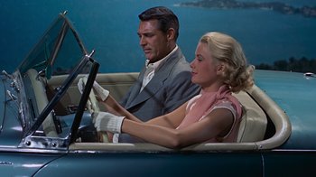 Movie still from “To Catch a Thief” (1955), directed by Alfred Hitchcock – A man and a woman sitting in a car; Medium shot, High angle