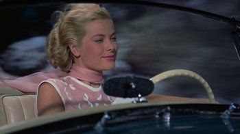 Movie still from “To Catch a Thief” (1955), directed by Alfred Hitchcock – A woman sitting in the driver's seat of a car; Close Up shot, Low angle