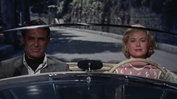Movie still from “To Catch a Thief” (1955), directed by Alfred Hitchcock – A man and a woman sitting in the back seat of a car; Medium shot, Low angle