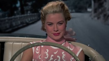 Movie still from “To Catch a Thief” (1955), directed by Alfred Hitchcock – A beautiful blonde woman sitting behind a steering wheel; Close Up shot, Over the shoulder angle
