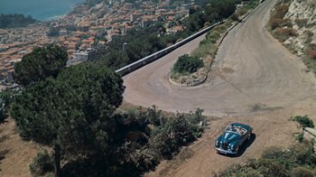 Movie still from “To Catch a Thief” (1955), directed by Alfred Hitchcock – An aerial view of a car driving down a road; Extreme Wide shot, High angle