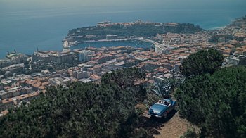 Movie still from “To Catch a Thief” (1955), directed by Alfred Hitchcock – An aerial view of a city with a car parked on top of a hill; Extreme Wide shot, High angle