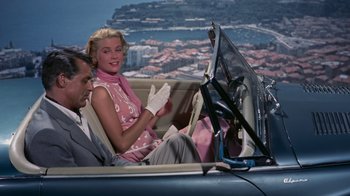 Movie still from “To Catch a Thief” (1955), directed by Alfred Hitchcock – A man and a woman sitting in the back of a car; Medium shot, High angle