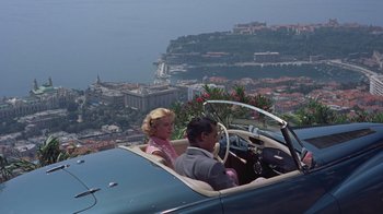 Movie still from “To Catch a Thief” (1955), directed by Alfred Hitchcock – A man and a woman sitting in the driver's seat of an antique car; Wide shot, High angle