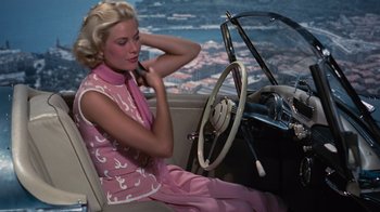 Movie still from “To Catch a Thief” (1955), directed by Alfred Hitchcock – A woman sitting in the driver's seat of an old car; Medium shot, High angle