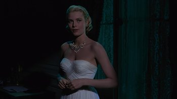 Movie still from “To Catch a Thief” (1955), directed by Alfred Hitchcock – A woman in a white dress is posing for a picture; Medium shot, Over the shoulder angle