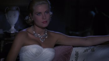 Movie still from “To Catch a Thief” (1955), directed by Alfred Hitchcock – A woman in a white dress sitting on a couch; Close Up shot, High angle