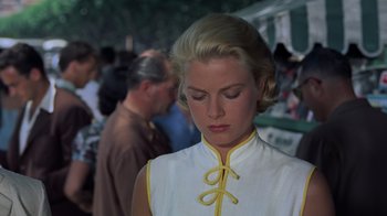 Movie still from “To Catch a Thief” (1955), directed by Alfred Hitchcock – A woman in a yellow and white dress looking down; Close Up shot, Low angle
