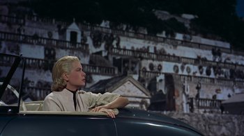 Movie still from “To Catch a Thief” (1955), directed by Alfred Hitchcock – A woman sitting in the back of an old car; Medium shot, Low angle