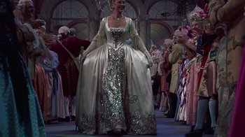 Movie still from “To Catch a Thief” (1955), directed by Alfred Hitchcock – A woman dressed in a costume is standing in front of a group of people; Wide shot, Low angle