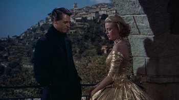 Movie still from “To Catch a Thief” (1955), directed by Alfred Hitchcock – A man and a woman standing next to each other in front of a stone wall; Medium shot, Low angle