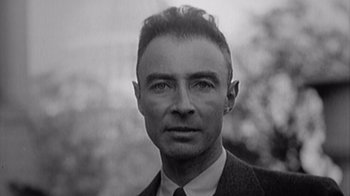 Movie still from “To End All War: Oppenheimer & the Atomic Bomb” (2023), directed by Christopher Cassel – An old black and white photo of a man in a suit and tie; Close Up shot, High angle