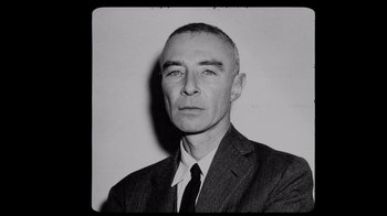 Movie still from “To End All War: Oppenheimer & the Atomic Bomb” (2023), directed by Christopher Cassel – An old black and white photo of a man in a suit; Close Up shot, Overhead angle