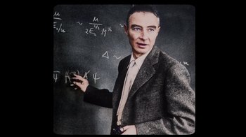 Movie still from “To End All War: Oppenheimer & the Atomic Bomb” (2023), directed by Christopher Cassel – A man in a suit and tie standing in front of a chalkboard; Close Up shot, Over the shoulder angle