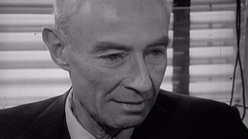 Movie still from “To End All War: Oppenheimer & the Atomic Bomb” (2023), directed by Christopher Cassel – An older man wearing a suit and tie looking to his left; Close Up shot, High angle