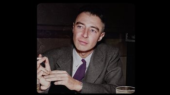 Movie still from “To End All War: Oppenheimer & the Atomic Bomb” (2023), directed by Christopher Cassel – A man sitting at a table smoking a cigarette; Close Up shot, Low angle