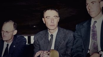 Movie still from “To End All War: Oppenheimer & the Atomic Bomb” (2023), directed by Christopher Cassel – An older man wearing a suit and tie; Medium shot, High angle