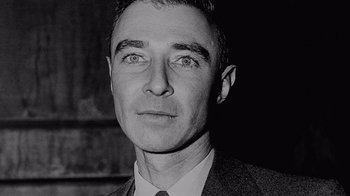 Movie still from “To End All War: Oppenheimer & the Atomic Bomb” (2023), directed by Christopher Cassel – An old black and white photo of a man in a suit and tie; Close Up shot, Overhead angle