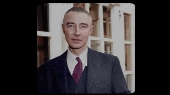 Movie still from “To End All War: Oppenheimer & the Atomic Bomb” (2023), directed by Christopher Cassel – A man in a suit and tie standing in front of a building; Close Up shot, High angle