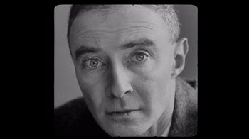 Movie still from “To End All War: Oppenheimer & the Atomic Bomb” (2023), directed by Christopher Cassel – An old black and white photo of a man's face; Close Up shot, Overhead angle