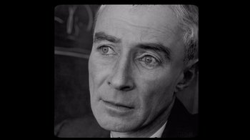Movie still from “To End All War: Oppenheimer & the Atomic Bomb” (2023), directed by Christopher Cassel – An older man in a suit and tie looking at the camera; Extreme Close Up shot, High angle