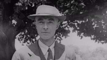 Movie still from “To End All War: Oppenheimer & the Atomic Bomb” (2023), directed by Christopher Cassel – An old black and white photo of a man wearing a hat; Close Up shot, Low angle