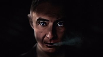 Movie still from “To End All War: Oppenheimer & the Atomic Bomb” (2023), directed by Christopher Cassel – A person smoking a cigarette; Close Up shot, Overhead angle