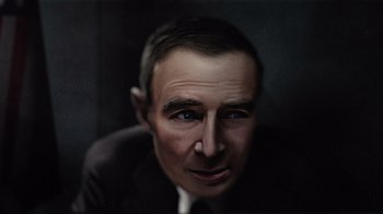 Movie still from “To End All War: Oppenheimer & the Atomic Bomb” (2023), directed by Christopher Cassel – A man in a suit and tie looking at the camera; Close Up shot, Overhead angle