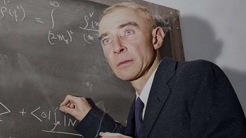 Movie still from “To End All War: Oppenheimer & the Atomic Bomb” (2023), directed by Christopher Cassel – A man in a suit and tie writing on a chalkboard; Close Up shot, Over the shoulder angle
