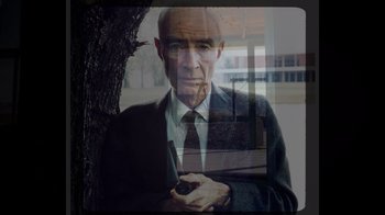 Movie still from “To End All War: Oppenheimer & the Atomic Bomb” (2023), directed by Christopher Cassel – An old man holding a cell phone in front of a tree; Medium shot, Low angle
