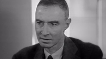 Movie still from “To End All War: Oppenheimer & the Atomic Bomb” (2023), directed by Christopher Cassel – An old black and white photo of a man in a suit and tie; Close Up shot, Low angle