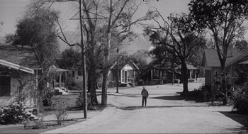 Movie still from “To Kill a Mockingbird” (1962), directed by Robert Mulligan – A man is walking down the street in a residential area; Extreme Wide shot, High angle