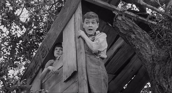 Movie still from “To Kill a Mockingbird” (1962), directed by Robert Mulligan – A boy and a girl standing next to each other on top of a wooden structure; Medium shot, Low angle