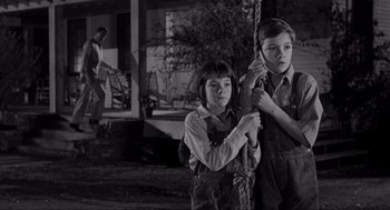 Movie still from “To Kill a Mockingbird” (1962), directed by Robert Mulligan – Two young children standing next to each other in front of a house; Medium shot, Low angle